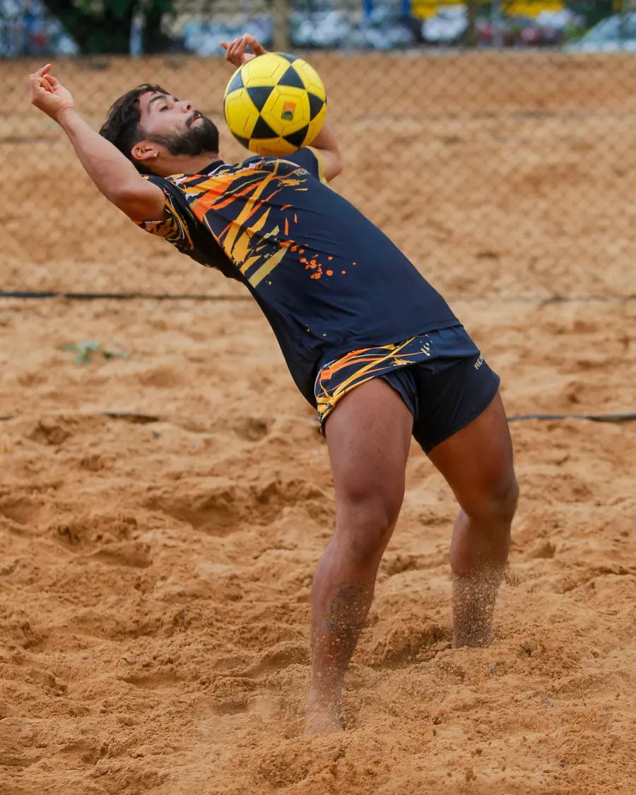 Jogador de futevôlei atacando a bola na areia