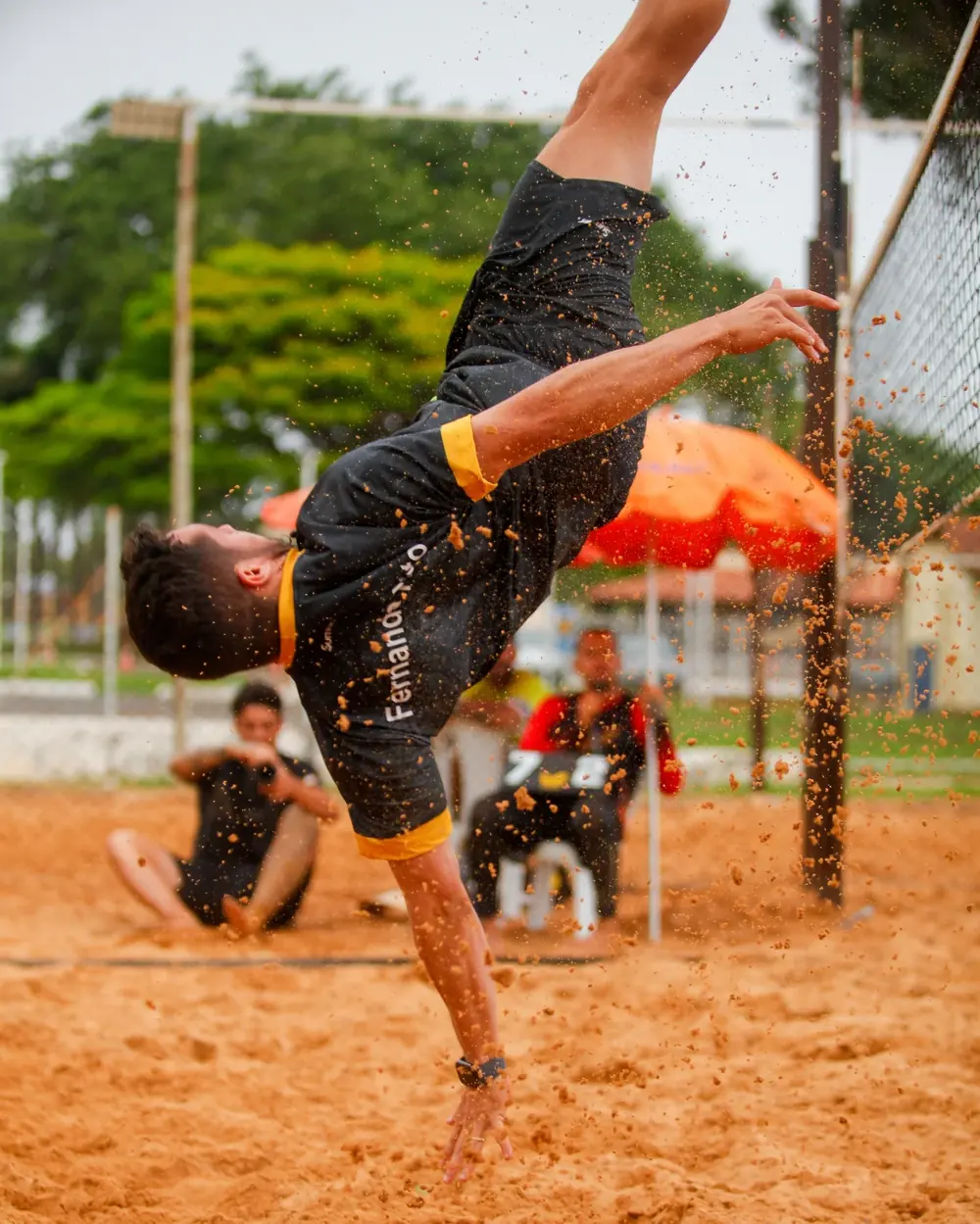 Atleta finalizando de bicicleta durante treino de futevôlei na areia do Reação Sports